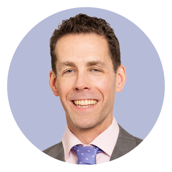 smiling dark haired man wearing suit with blue tie